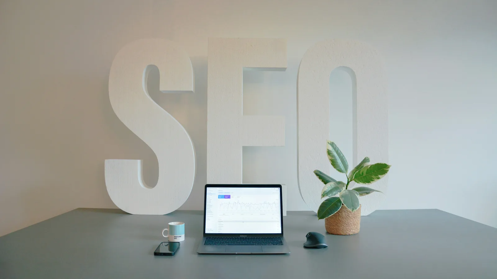 Lettres 3D « SEO » posées près d'un ordinateur portable