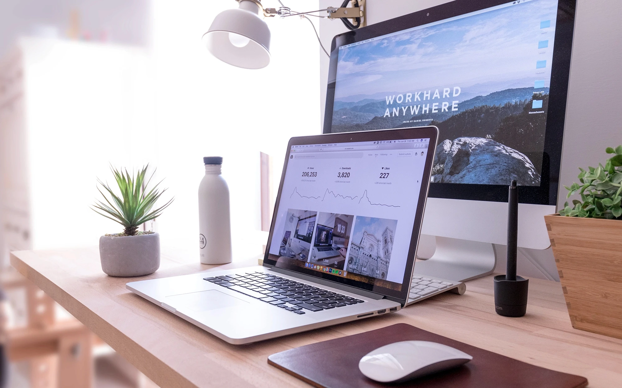 Bureau avec iMac et MacBook affichant « WORKHARD ANYWHERE »